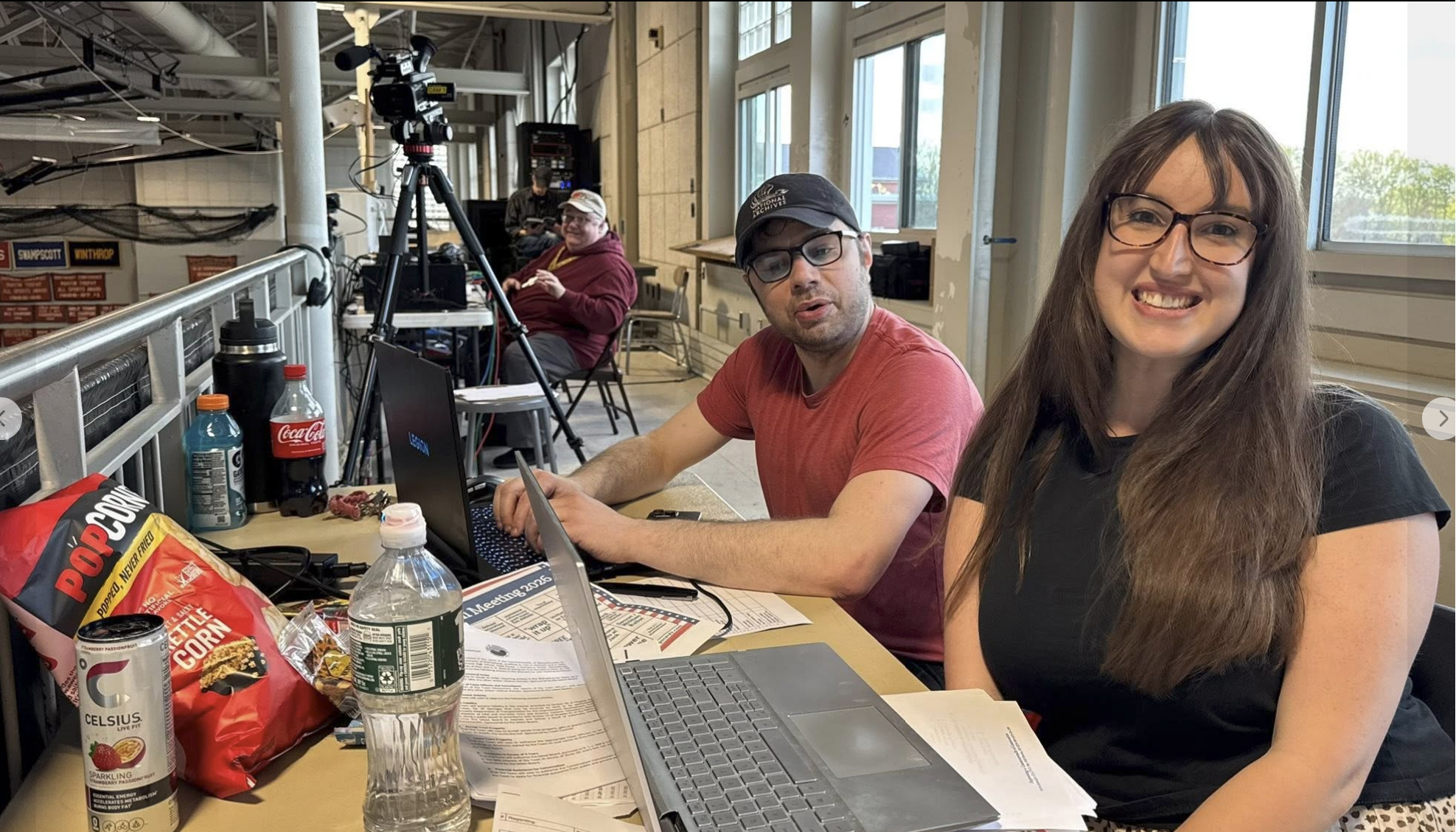 Sophia Harris of the Daily Item and Will Dowd of The Marblehead Independent set up laptops in the press balcony before the start of the 2026 Annual Town Meeting, with Jon Caswell of MHTV at the camera in the background.