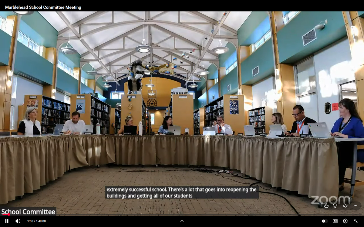 School Committee members seated at a long skirted table in a library